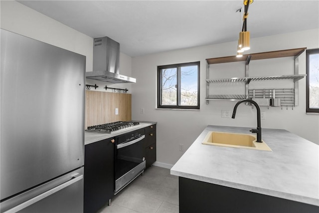 kitchen featuring wall chimney range hood, open shelves, light countertops, a sink, and stainless steel appliances