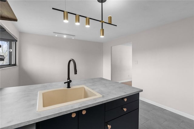 kitchen featuring light countertops, dark cabinets, hanging light fixtures, and a sink