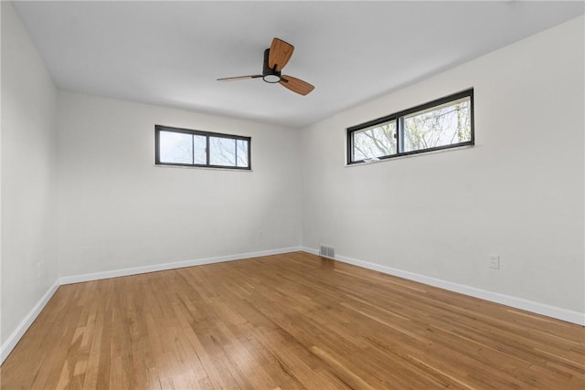 spare room featuring visible vents, light wood finished floors, plenty of natural light, and baseboards
