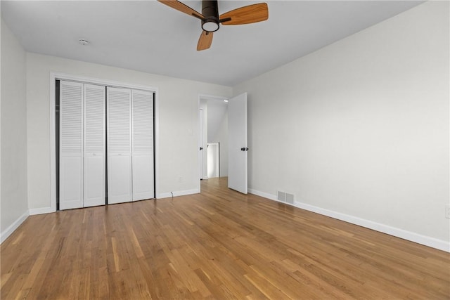 unfurnished bedroom with a closet, baseboards, visible vents, and light wood-style floors