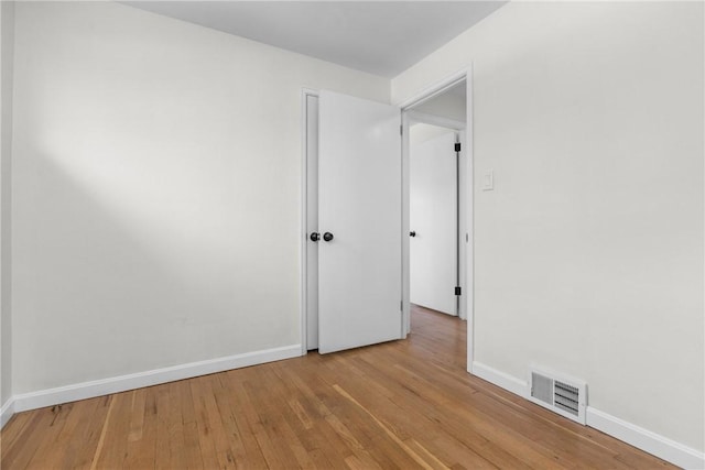 unfurnished room with visible vents, baseboards, and hardwood / wood-style flooring