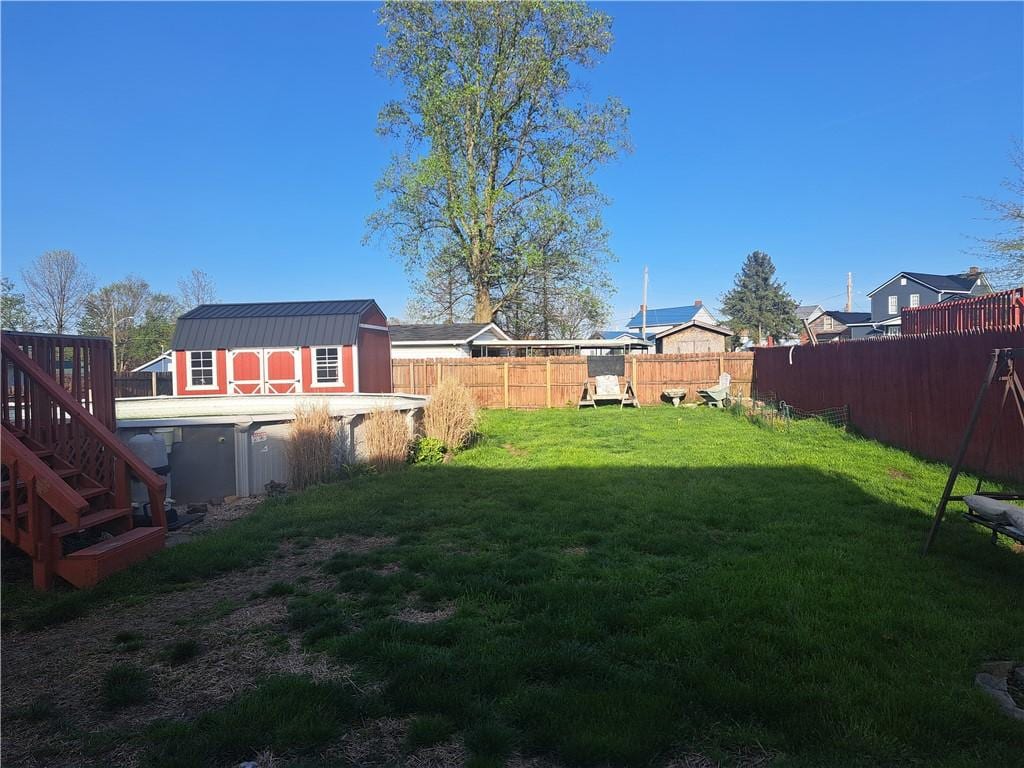 view of yard featuring a storage unit, an outdoor structure, and fence
