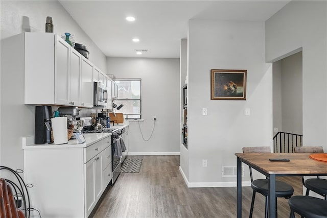 kitchen featuring white cabinets, light countertops, stainless steel appliances, baseboards, and dark wood-style floors