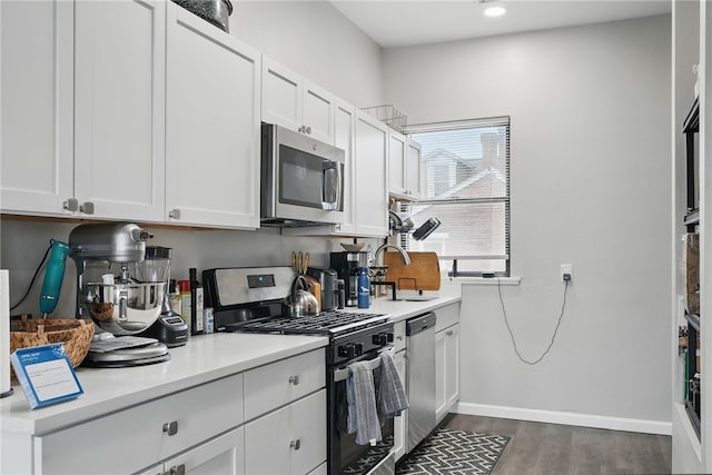 kitchen with a sink, appliances with stainless steel finishes, dark wood-style floors, and light countertops