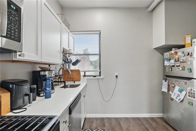 kitchen with dark wood-style floors, light countertops, white cabinetry, a sink, and stainless steel appliances