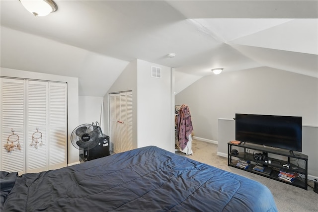 bedroom featuring multiple closets, visible vents, carpet flooring, and lofted ceiling