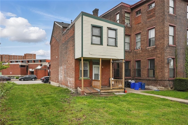 back of property with brick siding, a lawn, and a chimney
