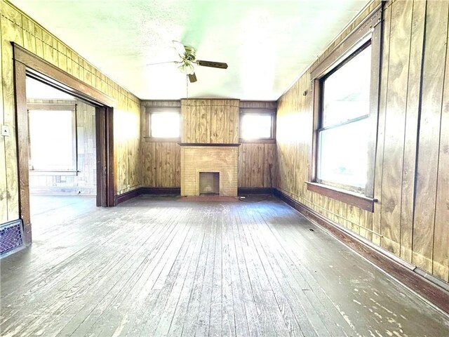 432 Boyles Ave, New Castle/2Nd, PA 16101 - unfurnished living room featuring wood-type flooring, wood walls, visible vents, a fireplace, and a ceiling fan