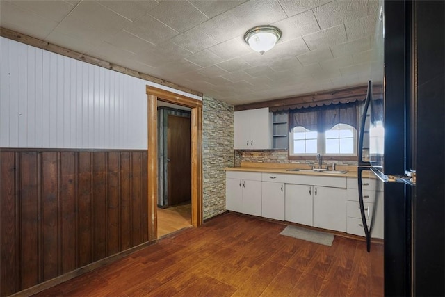 114 Angel Ave, Fairview Twp But, PA 16050 - kitchen with a sink, freestanding refrigerator, dark wood-style flooring, wooden walls, and white cabinetry