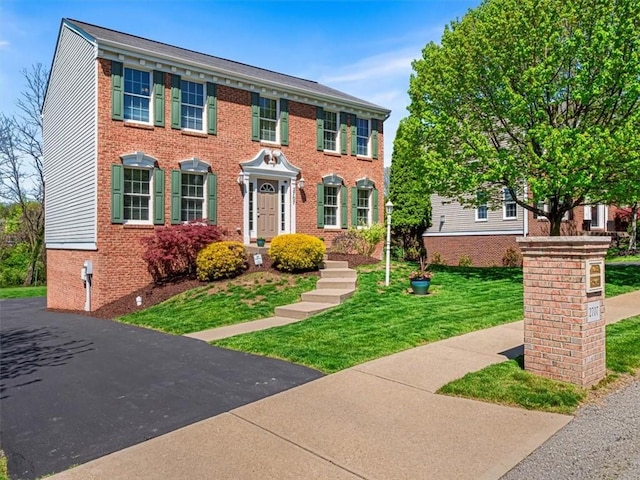 colonial-style house with a front yard and brick siding