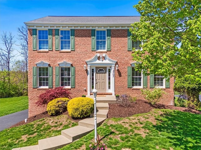 colonial inspired home with a front lawn and brick siding