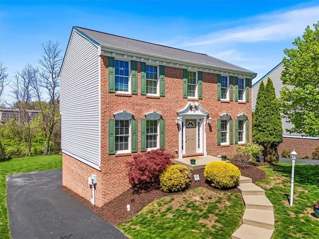 colonial house with brick siding and a front lawn