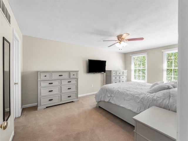 bedroom featuring baseboards, visible vents, light carpet, and ceiling fan