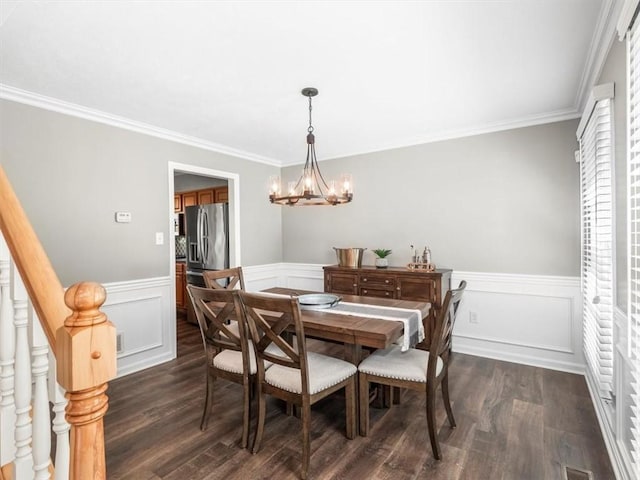 dining space with an inviting chandelier, wainscoting, dark wood-type flooring, visible vents, and ornamental molding