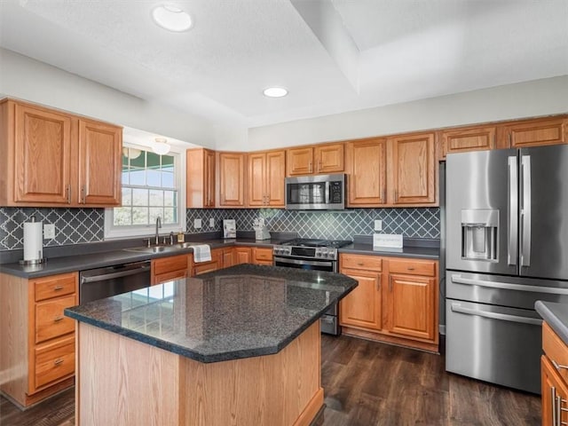 kitchen with a sink, dark wood finished floors, appliances with stainless steel finishes, and backsplash