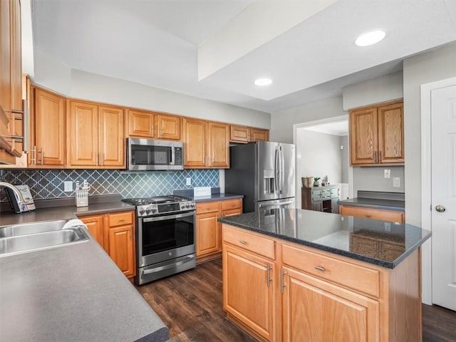 kitchen featuring a sink, appliances with stainless steel finishes, dark countertops, and dark wood-style floors