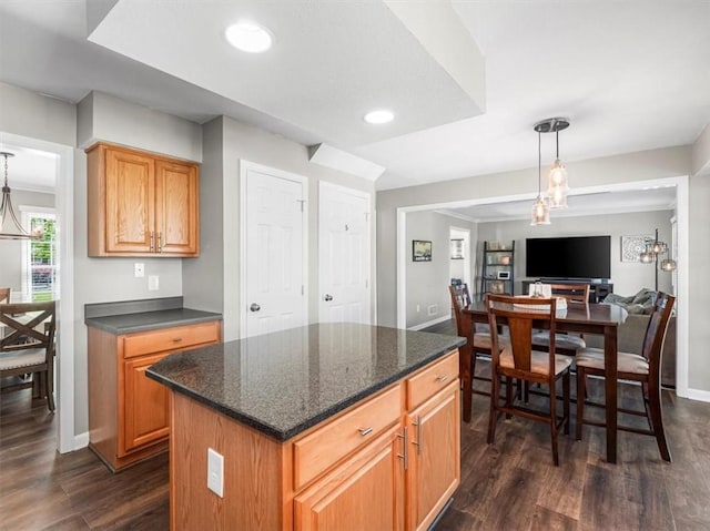 kitchen featuring dark wood-style flooring, a kitchen island, baseboards, open floor plan, and decorative light fixtures