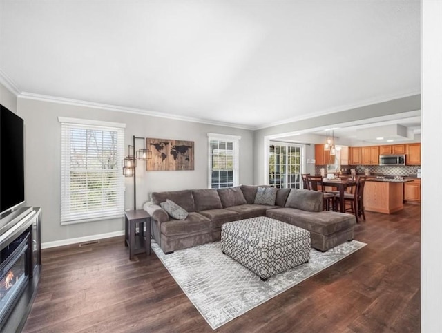 living area with crown molding, dark wood-style floors, and a wealth of natural light