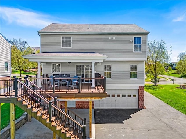 back of property featuring a lawn, stairs, an attached garage, and driveway