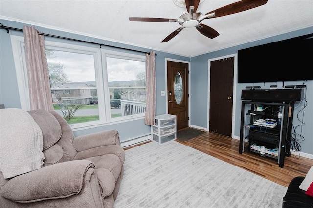 living area with wood finished floors, a ceiling fan, baseboards, and a baseboard heating unit