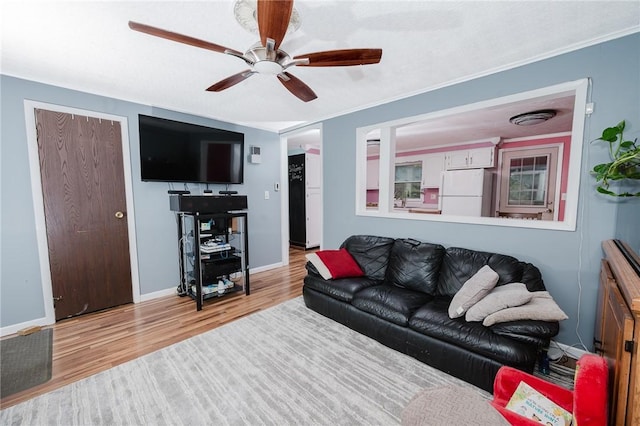 living area featuring a ceiling fan, baseboards, and wood finished floors