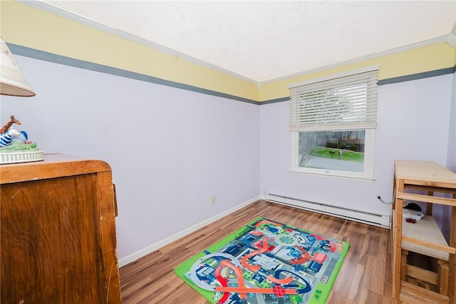 rec room featuring baseboards, a baseboard radiator, ornamental molding, and wood finished floors