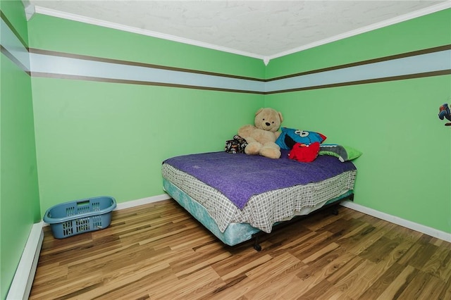 bedroom with baseboards, ornamental molding, wood finished floors, and baseboard heating