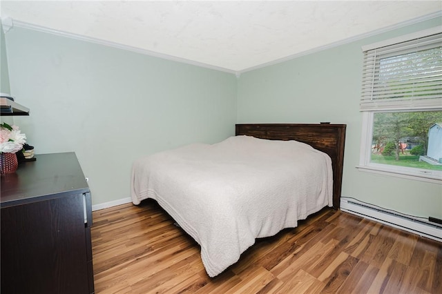bedroom featuring crown molding, wood finished floors, and baseboard heating