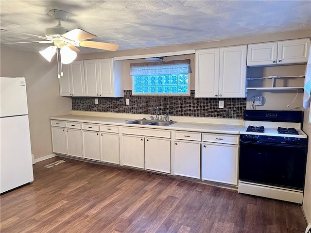 kitchen featuring a sink, light countertops, freestanding refrigerator, white cabinetry, and gas range oven