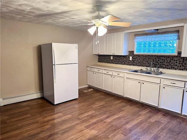 kitchen with a sink, light countertops, dark wood finished floors, freestanding refrigerator, and a baseboard radiator