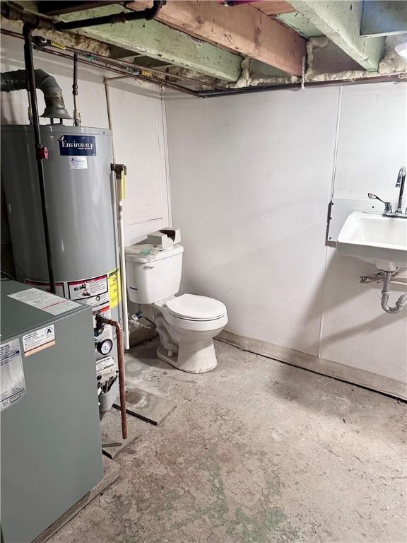 bathroom with water heater, toilet, and unfinished concrete floors