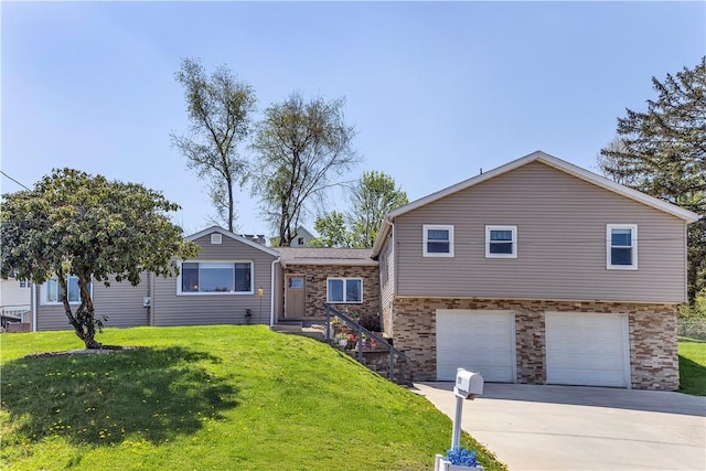 tri-level home with a garage, concrete driveway, and a front lawn