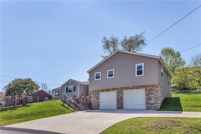 split level home with fence, an attached garage, driveway, and a front lawn