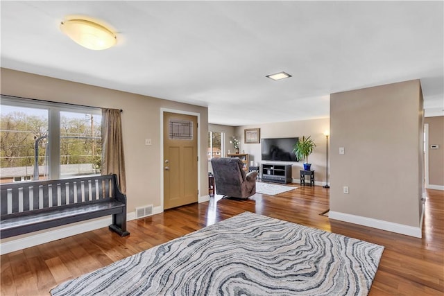 foyer entrance featuring visible vents, baseboards, and wood finished floors