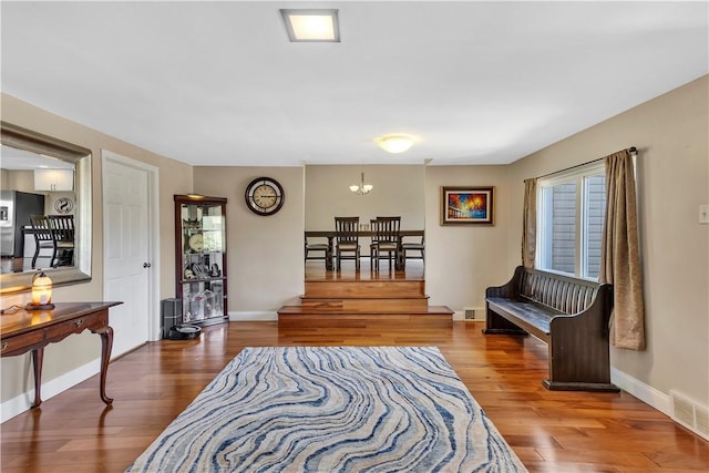 living area featuring baseboards, a notable chandelier, visible vents, and wood finished floors