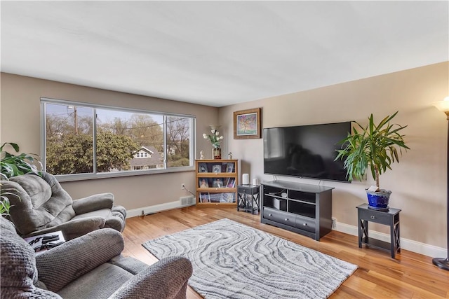 living room featuring visible vents, baseboards, and wood finished floors