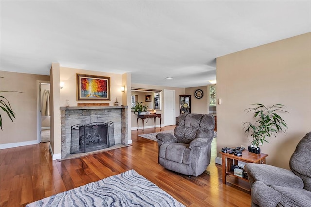 living room featuring baseboards, wood finished floors, and a fireplace