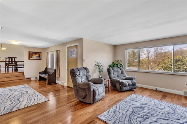 living room with baseboards, wood finished floors, a chandelier, and visible vents
