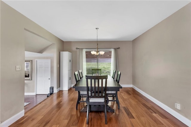 dining space featuring baseboards, wood finished floors, and a notable chandelier