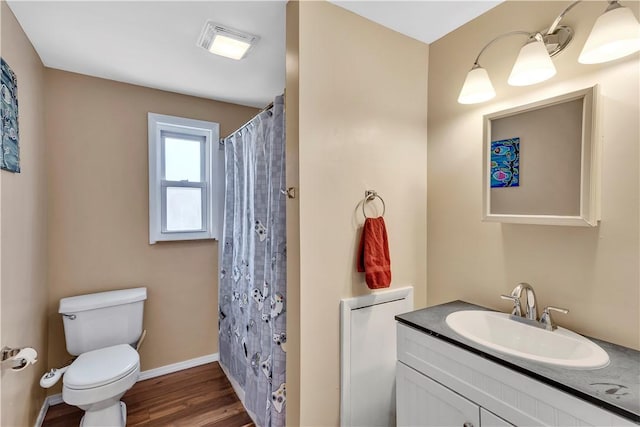 bathroom featuring visible vents, wood finished floors, vanity, baseboards, and toilet