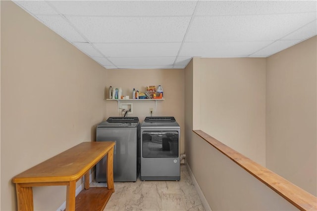 clothes washing area featuring laundry area, marble finish floor, baseboards, and washing machine and clothes dryer
