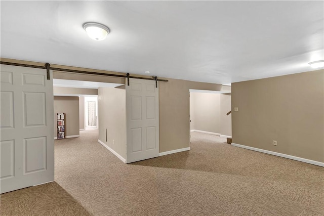 basement with baseboards, carpet, and a barn door