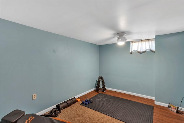 workout room featuring baseboards, a ceiling fan, and wood finished floors
