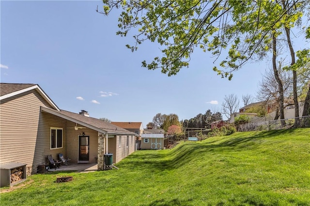 view of yard featuring an outdoor structure, a patio area, a shed, and fence