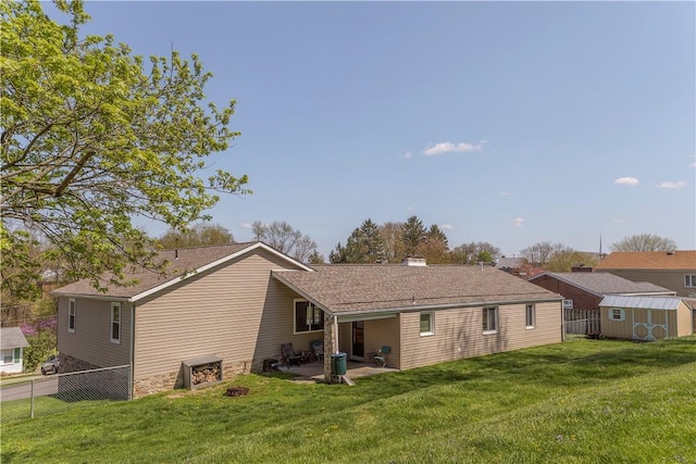 rear view of house with a storage shed, fence, an outdoor structure, and a lawn