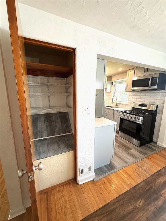 4402 Gateway Dr, Monroeville, PA 15146 - kitchen featuring decorative backsplash, light wood-style floors, light countertops, a sink, and stainless steel appliances