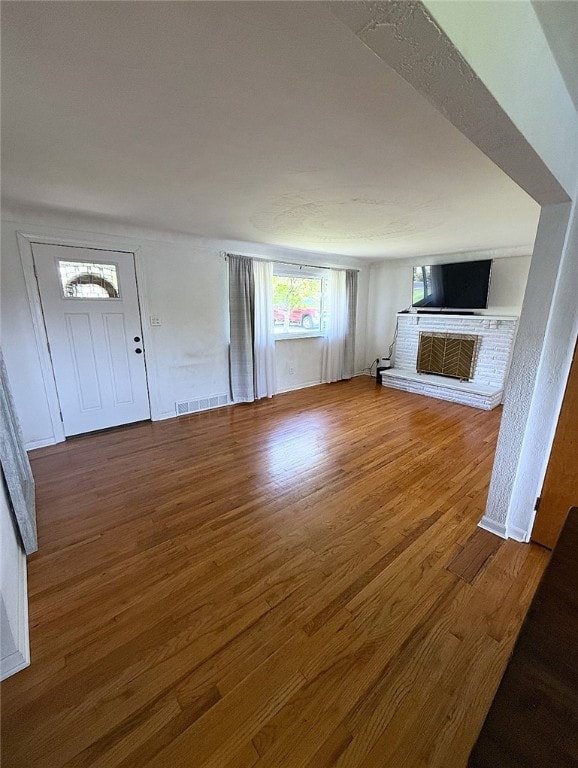 4402 Gateway Dr, Monroeville, PA 15146 - unfurnished living room with a brick fireplace, visible vents, and wood finished floors