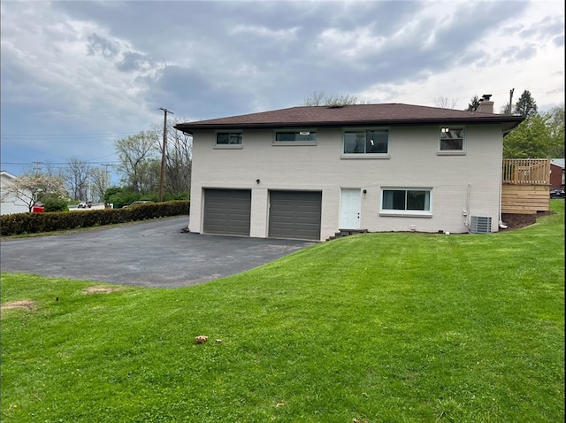 4402 Gateway Dr, Monroeville, PA 15146 - back of property with aphalt driveway, a wooden deck, a lawn, a chimney, and an attached garage