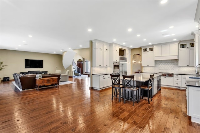 118 Lakeland Dr, Adams Twp, PA 16046 - kitchen with dark wood-style flooring, arched walkways, decorative backsplash, a kitchen bar, and a kitchen island