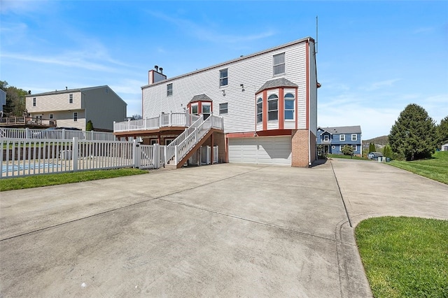 rear view of property with fence, stairs, brick siding, concrete driveway, and an attached garage